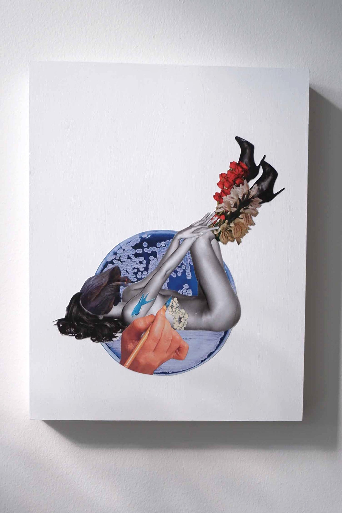 Original analog collage art of "botanical ink" a hybrid flower woman black heeled boots adorned with fresh flowers and a large hand painting ink blue birds on her naked body, an indigo blue circle spotted with white background