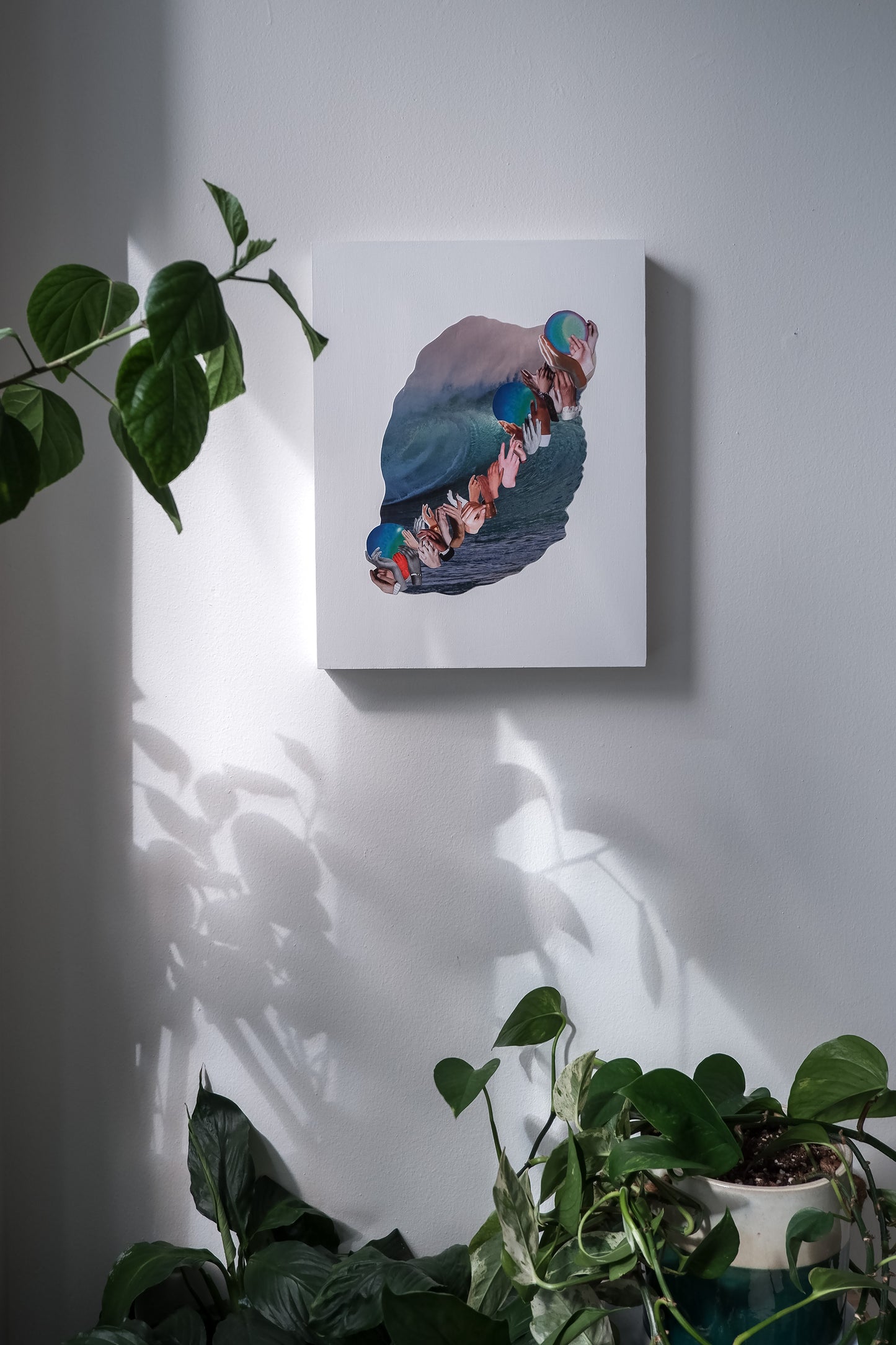 gallery wall with Three Waves collage art by artist Marissa Schiesser. Shadows of plants overcast on the art