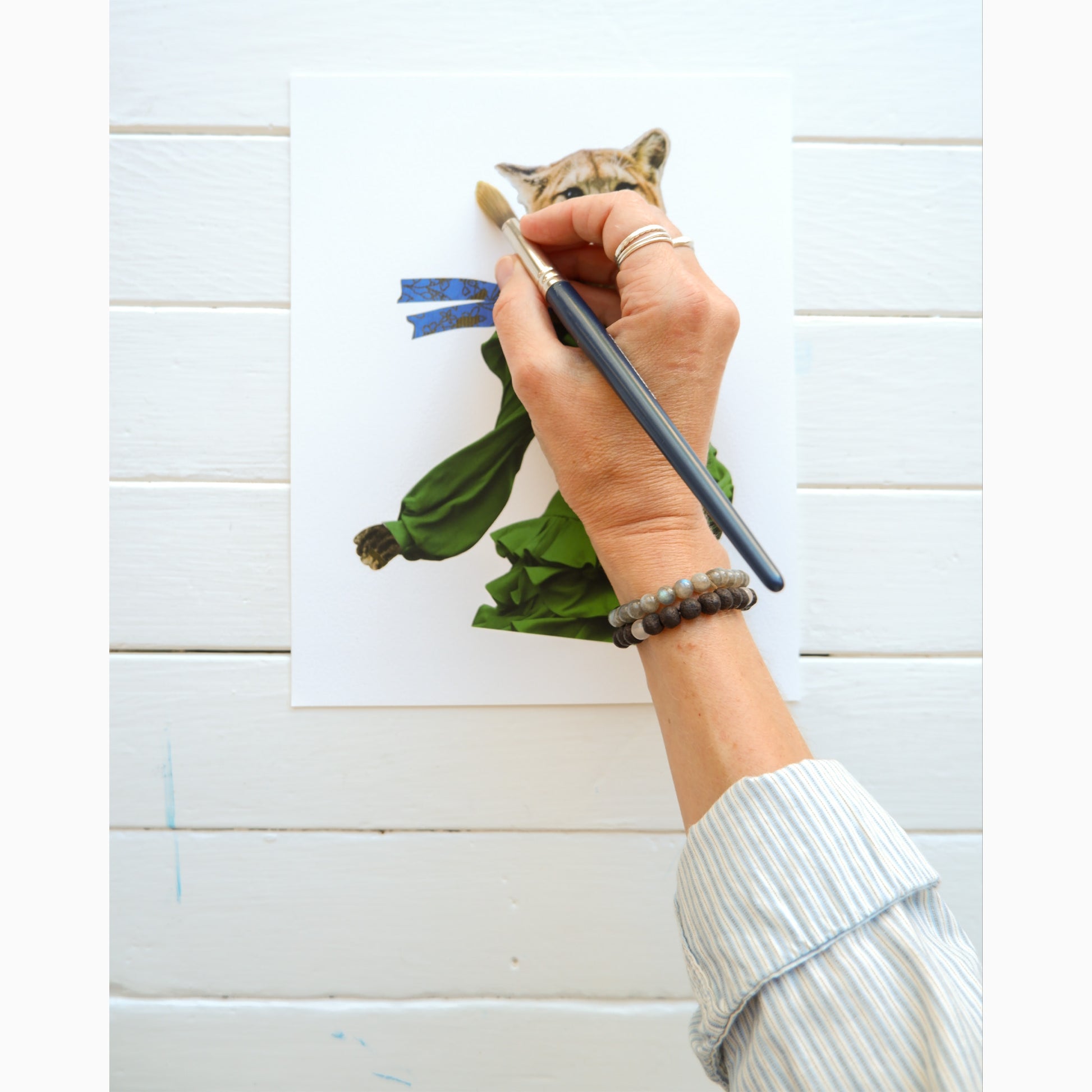 fine art print with artist's hand holding a paint brush showing the intention to add a hand painted embellishment to the print