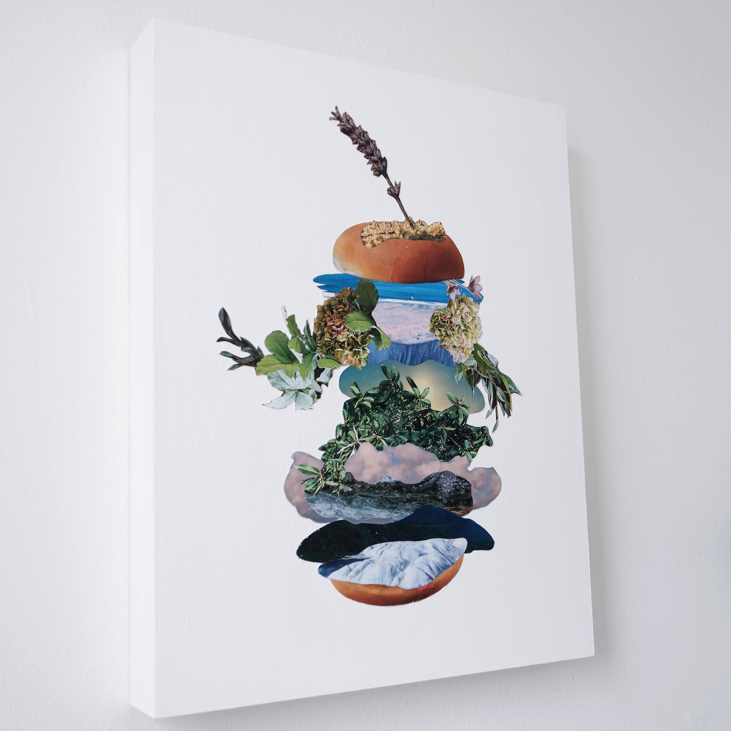 Angled view of Botanical Burger collage mounted on white painted wood Canadian made birch panel